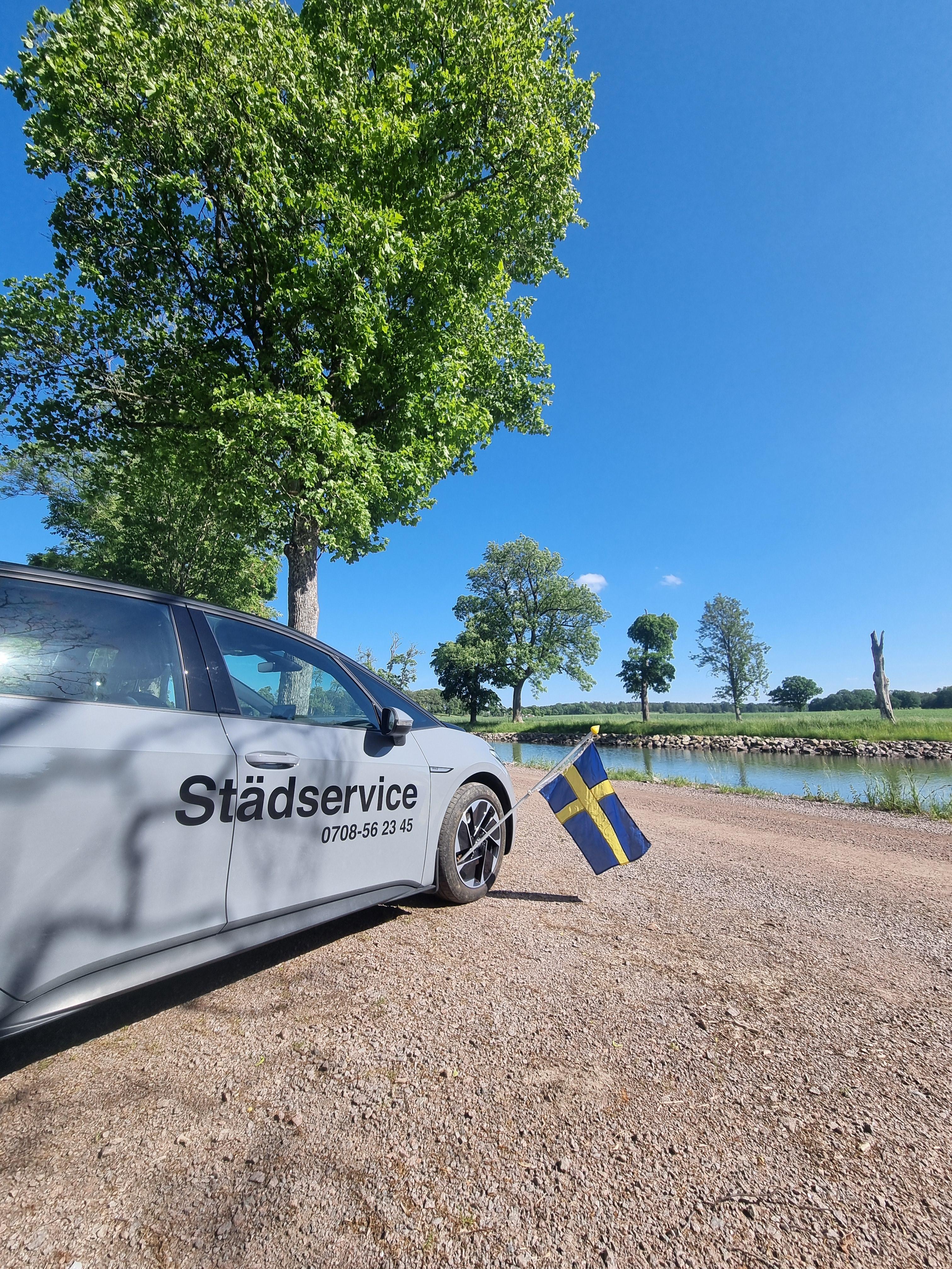 Three individuals in work uniforms and gloves are cleaning an indoor space with plants. One person is using a vacuum cleaner, while the others are engaged in cleaning tasks nearby. The setting features a modern interior with greenery and metal accents.